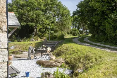 a patio with a table and a gravel road at Worvas Counthouse - Country Cottage - Hot Tub - Pet Friendly in St Ives