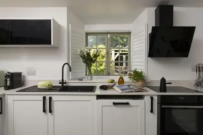 a kitchen with white cabinets and a sink and a window at Worvas Counthouse - Country Cottage - Hot Tub - Pet Friendly in St Ives