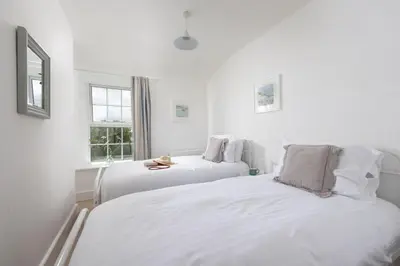 two beds in a room with white walls and windows at Worvas Counthouse - Country Cottage - Hot Tub - Pet Friendly in St Ives