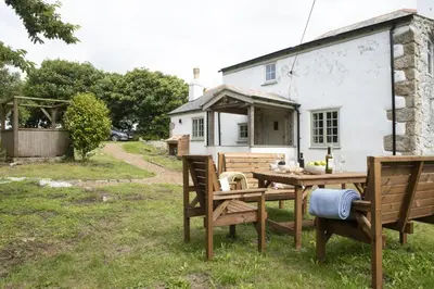 a table and chairs in a yard with a house at Worvas Counthouse - Country Cottage - Hot Tub - Pet Friendly in St Ives