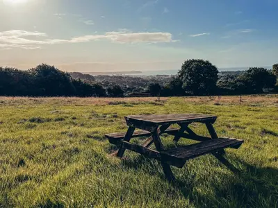 a wooden picnic table in a field of grass at Furnished Bell Tent 1 in St Austell