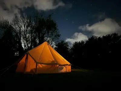 an orange tent in a field at night at Furnished Bell Tent 1 in St Austell