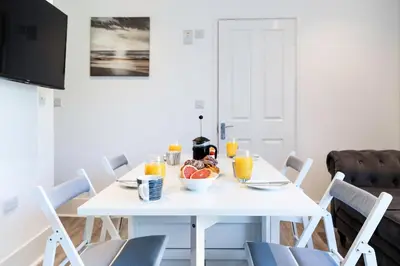 a white table with a bowl of fruit and orange juice at Another Nook in St Ives
