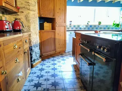 a kitchen with a black stove and a tile floor at Open Plan 3 Bedrooms Cornish stone house cottage in St Austell
