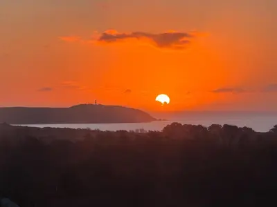 a sunset over a body of water with the sun at Barrel Cabin 1 in St Austell