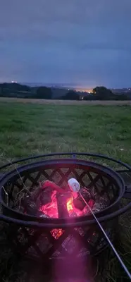 a fire pit in the middle of a field at Barrel Cabin 1 in St Austell