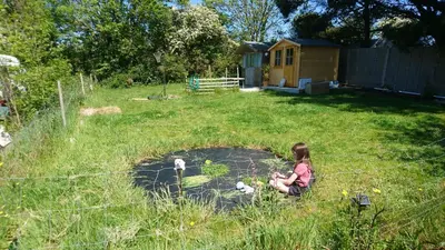 a little girl playing in a yard with a fence at Tiny House Glamping, sleeps up to 6 in Gweek
