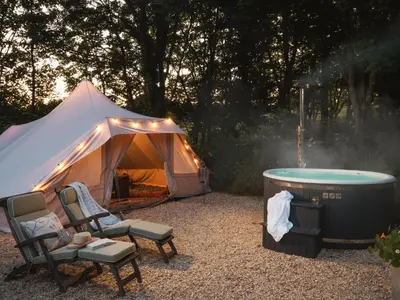 a tent with a hot tub and chairs next to a heater at Moonshine in Truro