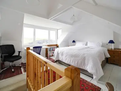 a bedroom with a white bed and a balcony at St Peters Cottage in Port Isaac