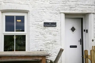 a white brick building with a door and a sign on it at St Peters Cottage in Port Isaac