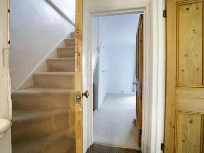 a hallway with stairs in a house with a door at St Peters Cottage in Port Isaac