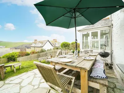 a wooden table with an umbrella on a patio at St Peters Cottage in Port Isaac