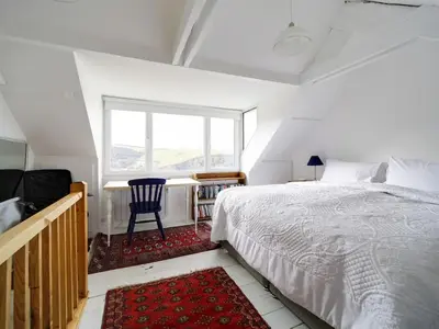 a bedroom with a bed and a window and a chair at St Peters Cottage in Port Isaac