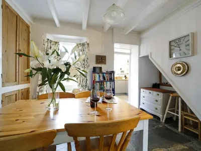 a dining room table with a vase of flowers on it at St Peters Cottage in Port Isaac