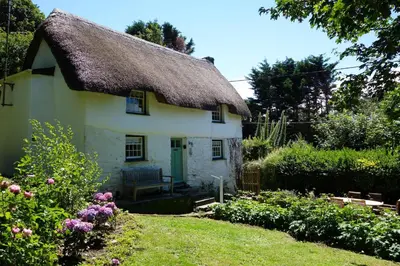 a thatch roofed house with a garden at Finest Retreats - Old Lanvean Cottage in Saint Mawgan
