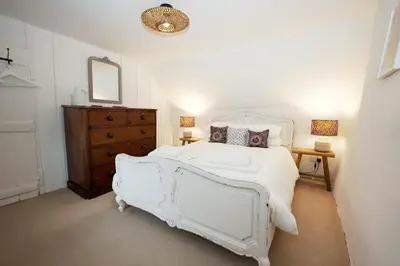a bedroom with a white bed and a dresser and a mirror at Finest Retreats - Old Lanvean Cottage in Saint Mawgan
