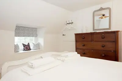 a white bedroom with a white bed and a dresser at Finest Retreats - Old Lanvean Cottage in Saint Mawgan
