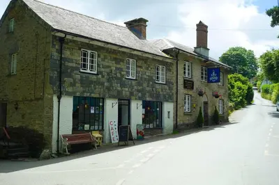 an old brick building with a bench on a street at Finest Retreats - Old Lanvean Cottage in Saint Mawgan