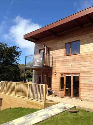 a wooden house with a deck and a balcony at Anemone in Porthtowan