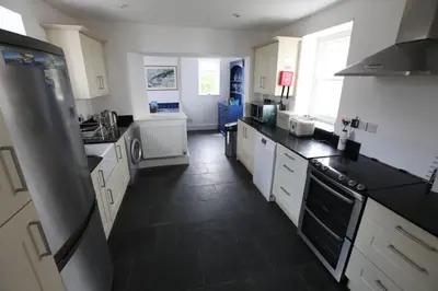 a kitchen with white cabinets and a black floor at Sea Haven in Port Isaac