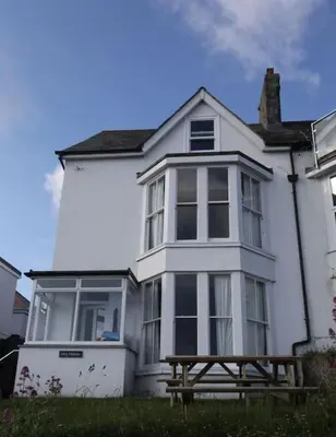 a white house with a wooden bench in front of it at Sea Haven in Port Isaac