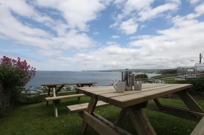 a wooden picnic table with a view of the ocean at Sea Haven in Port Isaac