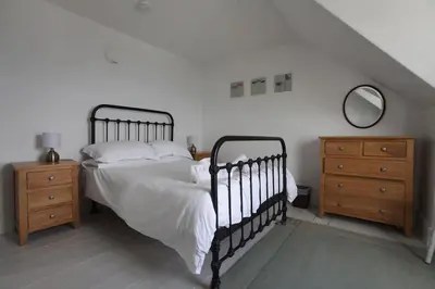 a bedroom with a bed and two dressers and a mirror at Sea Haven in Port Isaac