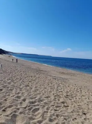 a beach with people walking on the sand and the ocean at Small self contained room in Porthleven
