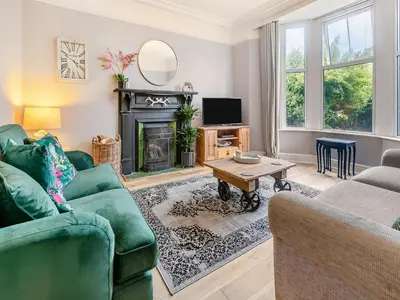 a living room with a green couch and a fireplace at Lanner Moon in Carnbrea
