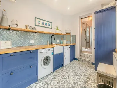 a kitchen with blue cabinets and a washing machine at Lanner Moon in Carnbrea
