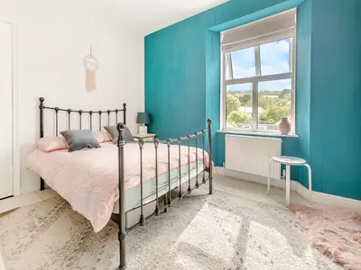 a bedroom with a bed and a blue wall at Lanner Moon in Carnbrea