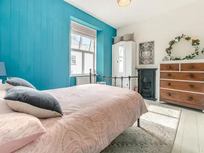 a bedroom with blue walls and a bed with pillows at Lanner Moon in Carnbrea