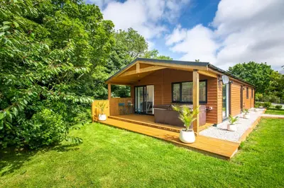 a small house with a deck and grass at Maple Lodge in Hayle