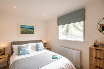 a bedroom with a bed with blue pillows and a window at Maple Lodge in Hayle