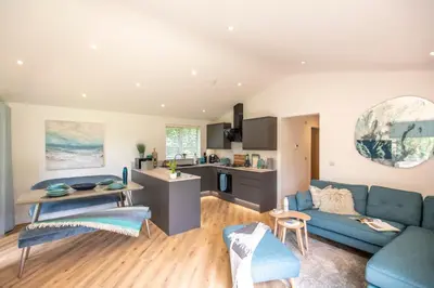 a living room with a blue couch and a kitchen at Maple Lodge in Hayle