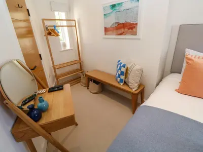 a bedroom with a bed and a table and a mirror at Sea La Vie in St Ives