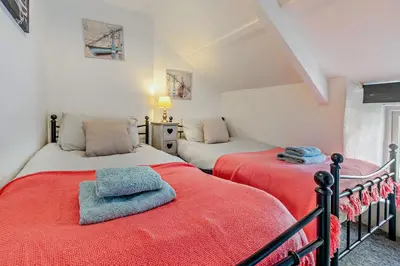 a bedroom with two beds with red sheets at 2 Bed in Delabole oc-r29780 in Delabole