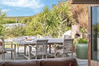 a wooden table and chairs on a patio at 4 Bed in Mawgan Porth oc-h29763 in Mawgan Porth