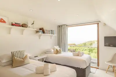two beds in a room with a large window at 4 Bed in Mawgan Porth oc-h29763 in Mawgan Porth