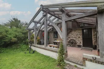 a large wooden pergola on a stone house at Horseshoe Cottage in Newquay
