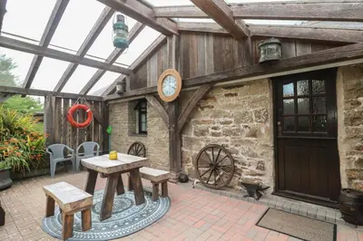 a conservatory with a table and a clock on the wall at Horseshoe Cottage in Newquay