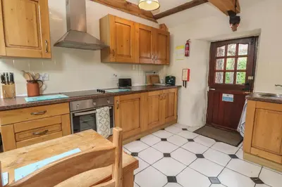 a kitchen with wooden cabinets and a table in it at Horseshoe Cottage in Newquay