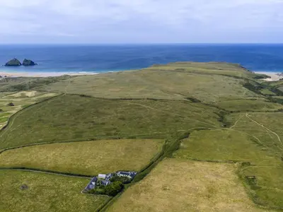 an aerial view of a green field with the ocean at Horseshoe Cottage in Newquay