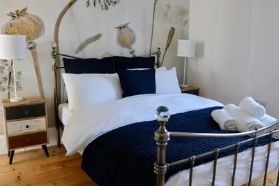 a bedroom with a bed with blue and white pillows at Flip Flop Flat, Sea Views, Short Stroll to Beaches in Newquay