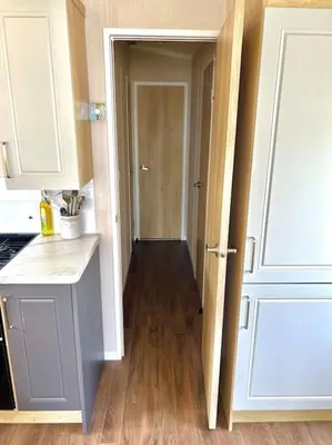 a kitchen with a door open to a hallway at The Driftwood Den in Tywardreath