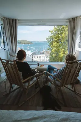 two people sitting in chairs looking out of a window at Stunning High Street Townhouse With Sea Views & Parking at 'Tide View Townhouse' in Falmouth