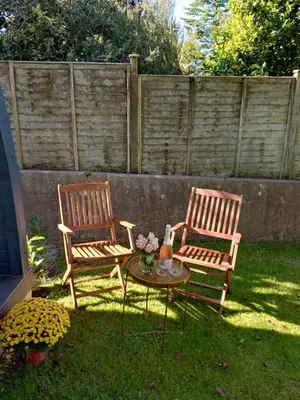 two wooden chairs and a table with flowers on the grass at Beautiful and Cosy Garden Pod Saintives in Carbis Bay