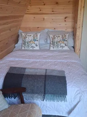 a large bed in a room with a wooden wall at Beautiful and Cosy Garden Pod Saintives in Carbis Bay