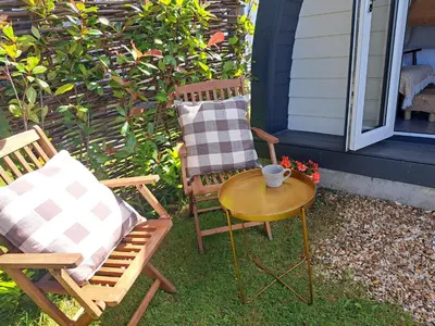 two chairs and a table next to a house at Beautiful and Cosy Garden Pod Saintives in Carbis Bay