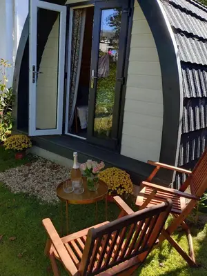 two chairs and a table in front of a house at Beautiful and Cosy Garden Pod Saintives in Carbis Bay